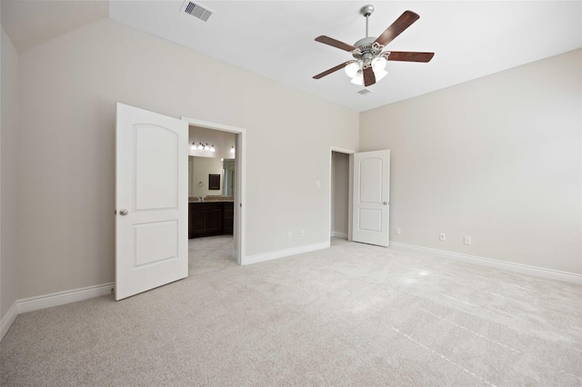 unfurnished bedroom with light colored carpet, visible vents, vaulted ceiling, baseboards, and ensuite bath