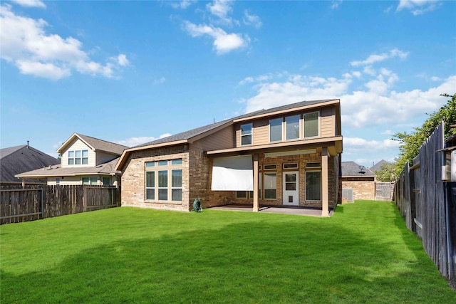 back of property with a fenced backyard, a lawn, a patio area, and brick siding