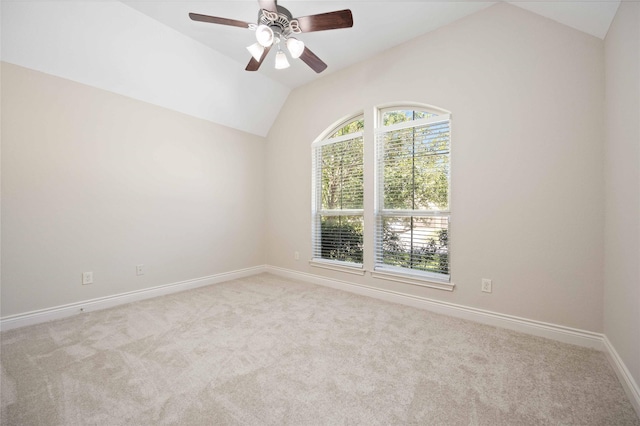 spare room featuring carpet flooring, baseboards, vaulted ceiling, and ceiling fan