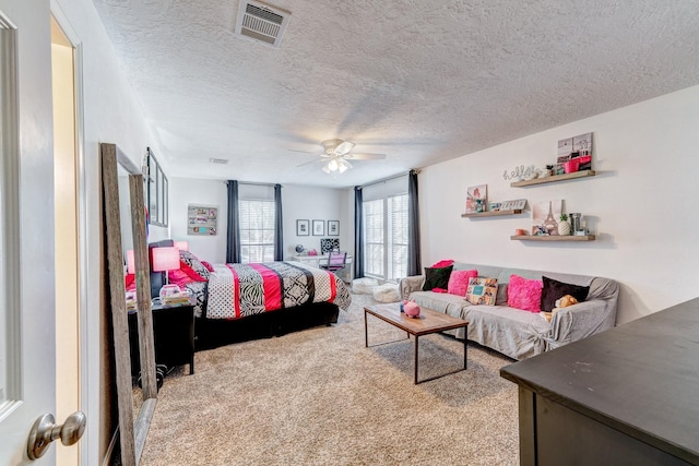 bedroom with a textured ceiling, carpet, visible vents, and a ceiling fan