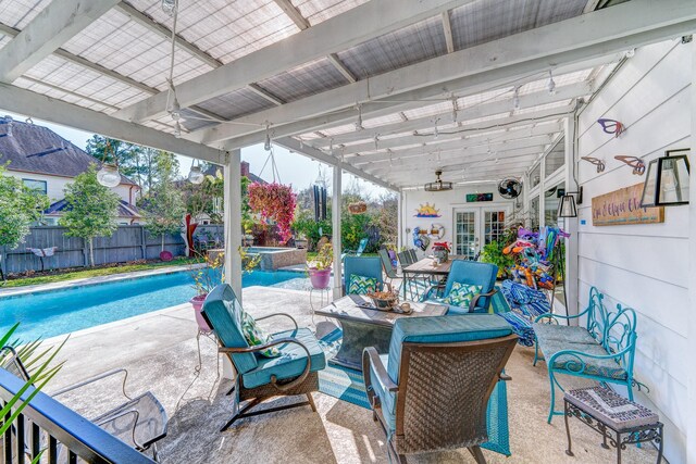 view of patio / terrace featuring a fenced backyard, a ceiling fan, a pool with connected hot tub, and french doors