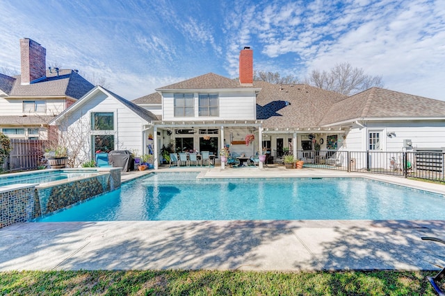 view of swimming pool with a pool with connected hot tub, a patio, and fence