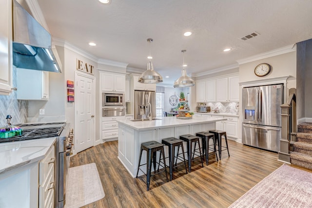 kitchen with a warming drawer, stainless steel appliances, white cabinets, wall chimney exhaust hood, and visible vents