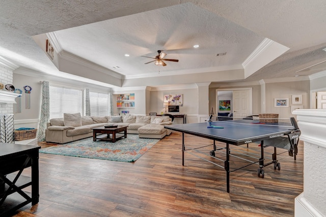 rec room with hardwood / wood-style flooring, a textured ceiling, a raised ceiling, and crown molding