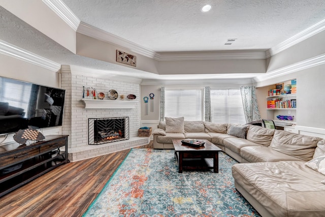 living room featuring a fireplace, wood finished floors, a textured ceiling, and ornamental molding