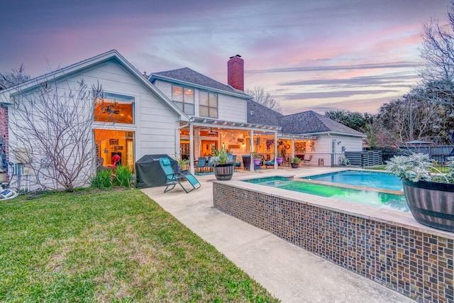back of house at dusk with a chimney, fence, a yard, a patio, and a fenced in pool