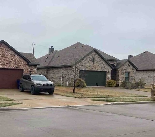 exterior space featuring roof with shingles, a chimney, concrete driveway, a garage, and brick siding
