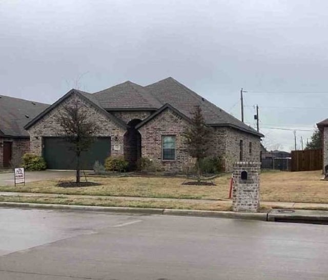 french country home with brick siding, an attached garage, fence, and driveway