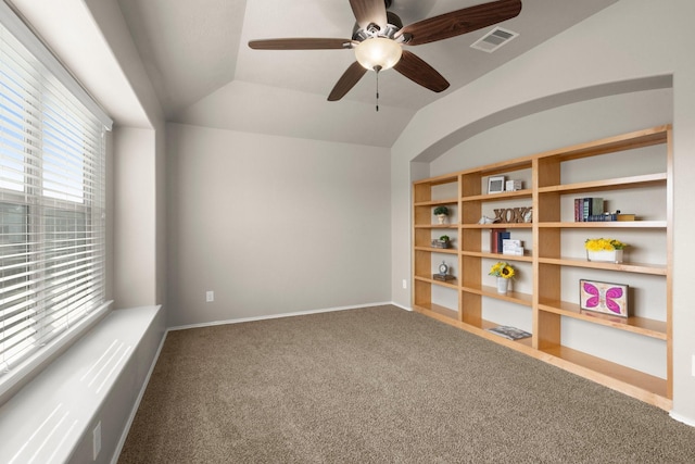 carpeted empty room with vaulted ceiling, a ceiling fan, visible vents, and baseboards