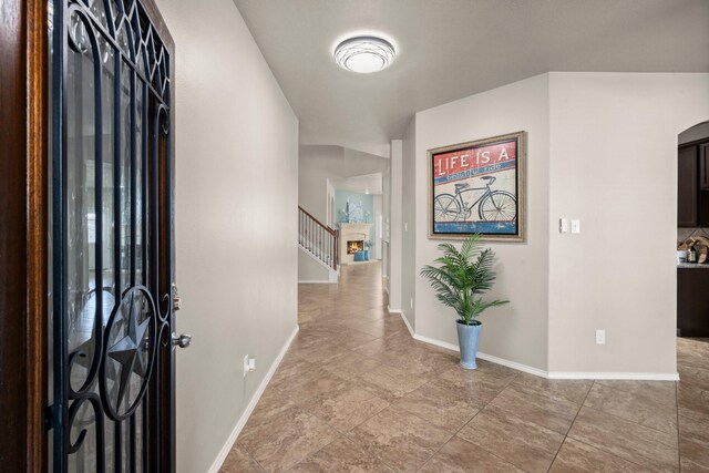 foyer entrance featuring arched walkways, stairs, baseboards, and light tile patterned floors