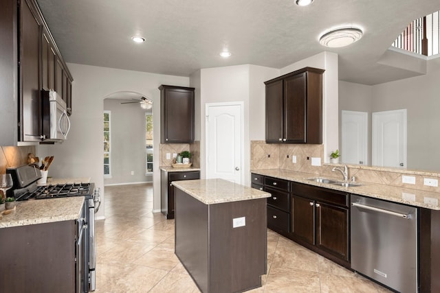 kitchen with decorative backsplash, a sink, appliances with stainless steel finishes, ceiling fan, and dark brown cabinets