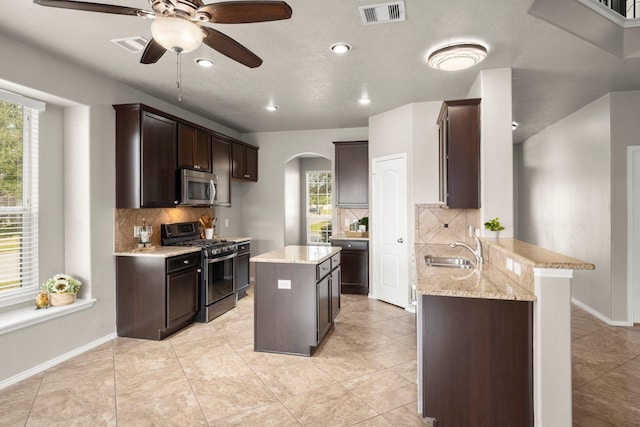 kitchen featuring a sink, arched walkways, a peninsula, appliances with stainless steel finishes, and visible vents