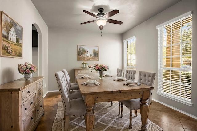 dining area featuring ceiling fan, arched walkways, and baseboards