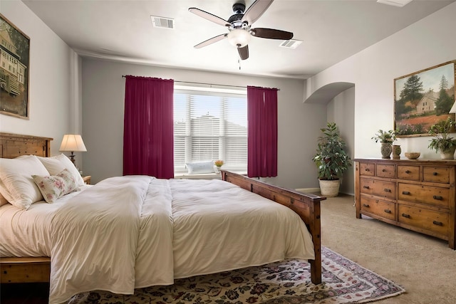 bedroom with ceiling fan, arched walkways, carpet flooring, and visible vents