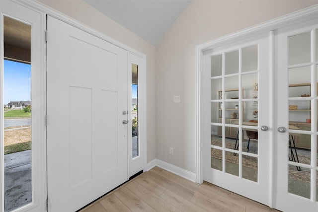 foyer entrance with lofted ceiling, french doors, light wood-style floors, and baseboards