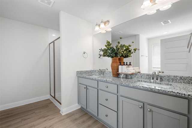 bathroom with a shower stall, wood finished floors, visible vents, and a sink
