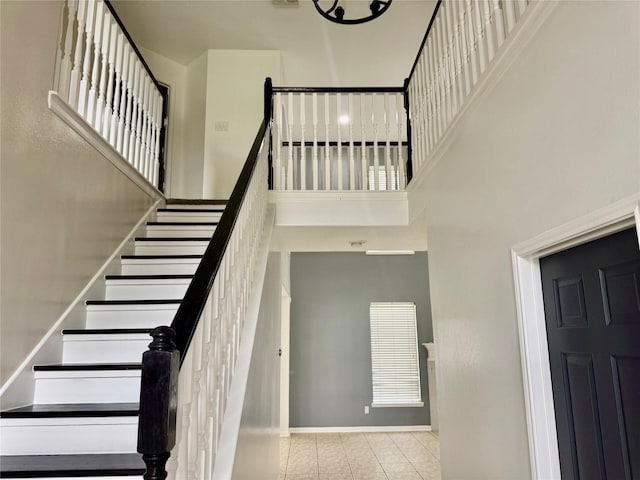 stairway with a high ceiling, tile patterned floors, and baseboards