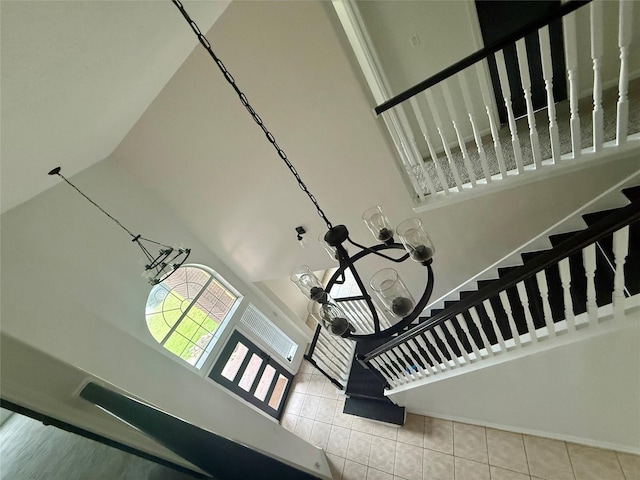 stairway featuring a high ceiling, tile patterned flooring, and baseboards
