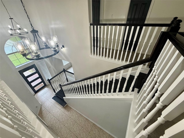 stairway with a notable chandelier and tile patterned floors