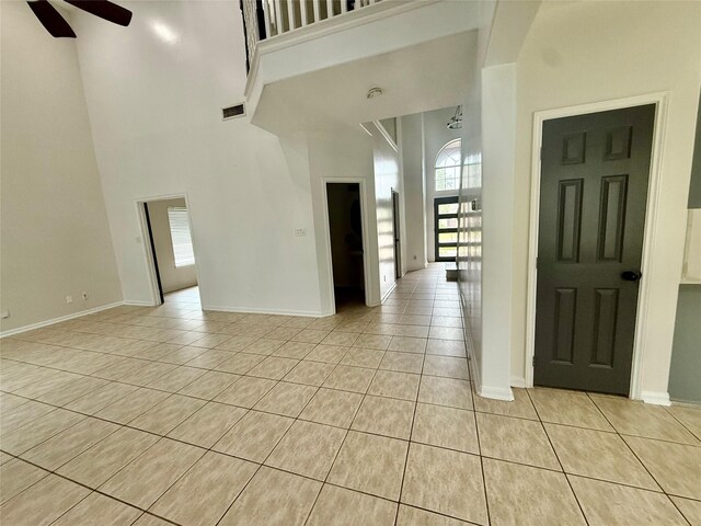 interior space featuring light tile patterned flooring, a high ceiling, a ceiling fan, and a healthy amount of sunlight