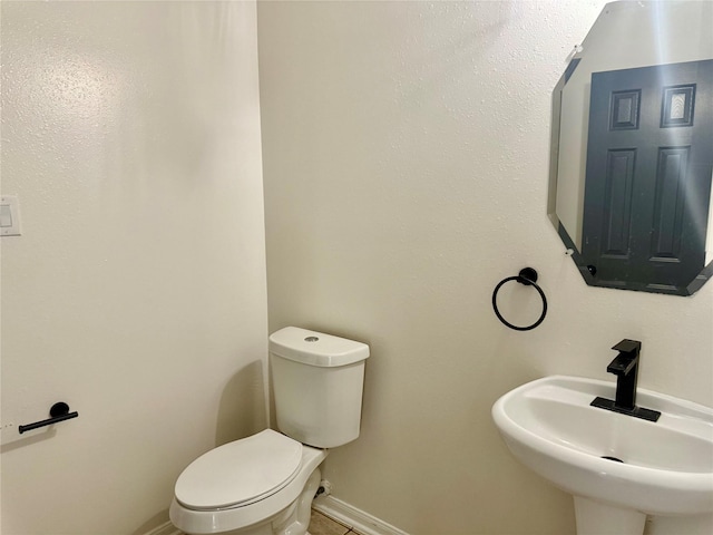 bathroom featuring baseboards, a sink, and toilet
