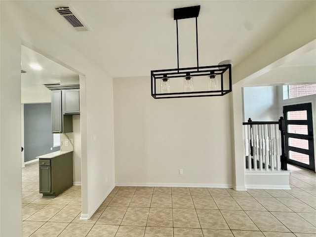unfurnished dining area featuring light tile patterned flooring, visible vents, and baseboards