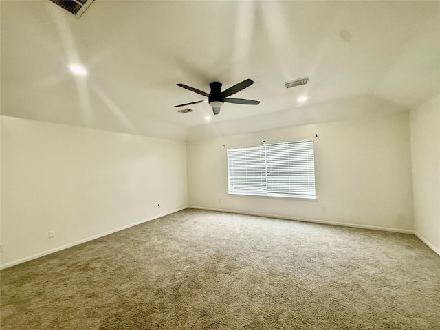 carpeted spare room with visible vents, baseboards, and ceiling fan
