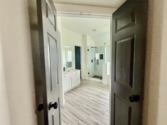 full bath with a shower stall, vanity, wood finished floors, and visible vents