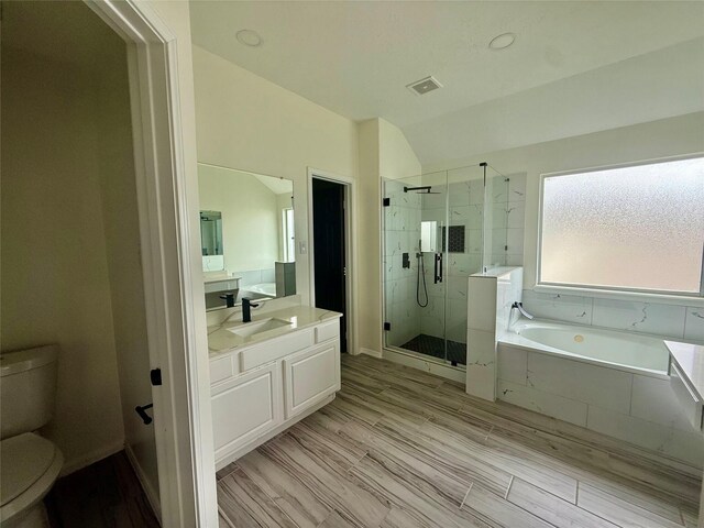 bathroom featuring a stall shower, toilet, lofted ceiling, a garden tub, and vanity