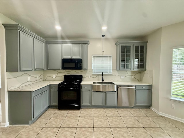 kitchen with a sink, black appliances, decorative backsplash, gray cabinets, and a healthy amount of sunlight