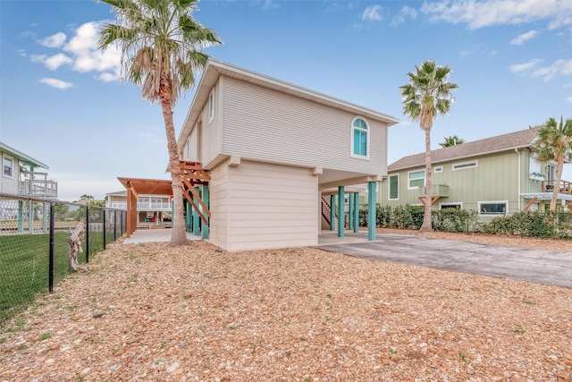 16520 Barbados Way, Jamaica Beach, TX 77554 - back of house featuring a carport, aphalt driveway, fence, and stairs
