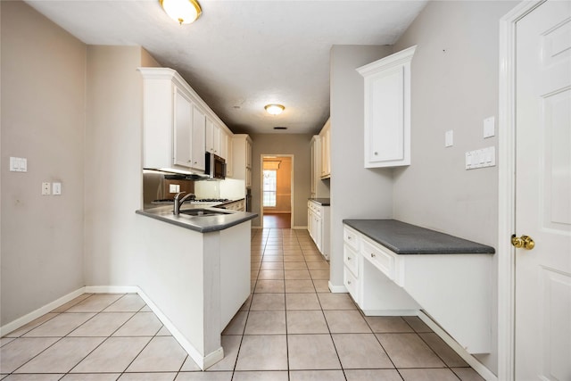 24526 Haigshire Dr, Tomball, TX 77375 - kitchen with stainless steel microwave, dark countertops, light tile patterned floors, and white cabinetry
