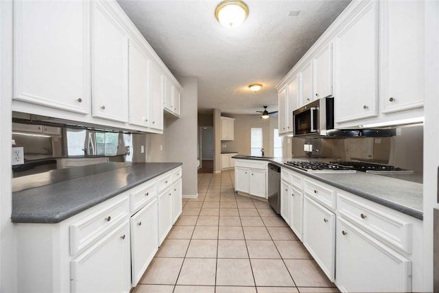 24526 Haigshire Dr, Tomball, TX 77375 - kitchen with stainless steel appliances, light tile patterned floors, white cabinetry, ceiling fan, and a textured ceiling