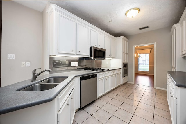 24526 Haigshire Dr, Tomball, TX 77375 - kitchen featuring stainless steel appliances, white cabinets, light tile patterned flooring, a chandelier, and a textured ceiling