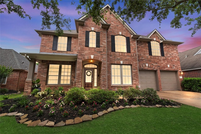 traditional-style home with driveway, a yard, an attached garage, and brick siding