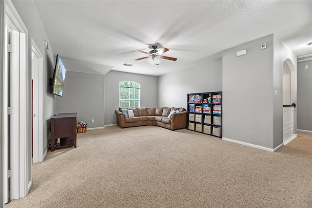 living room featuring a textured ceiling, ceiling fan, baseboards, and carpet floors