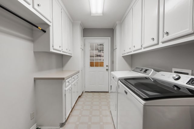 clothes washing area featuring light floors, washer and dryer, and cabinet space