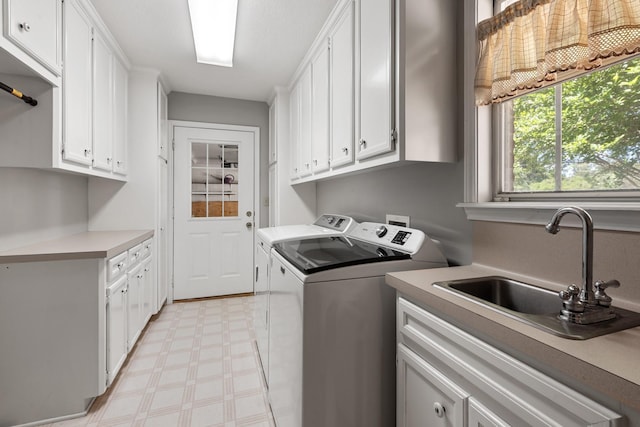 washroom with washing machine and dryer, a sink, light floors, and cabinet space