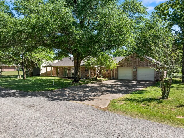 single story home with brick siding, an attached garage, a front lawn, and aphalt driveway