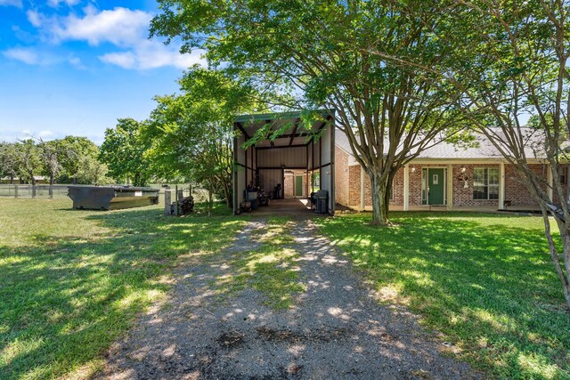 view of yard featuring driveway, a carport, and fence