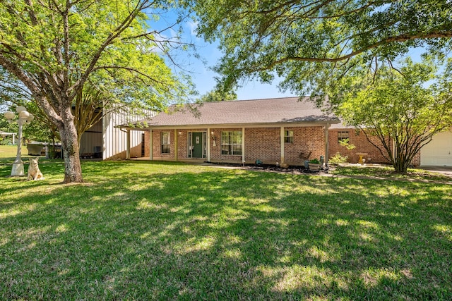 back of house featuring a lawn, brick siding, and a garage