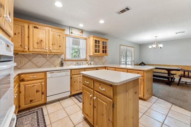 kitchen featuring a peninsula, visible vents, a sink, and white appliances