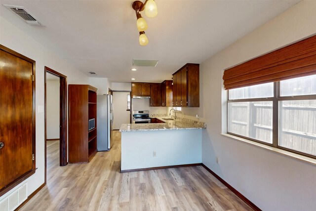 kitchen with a peninsula, visible vents, appliances with stainless steel finishes, and a sink