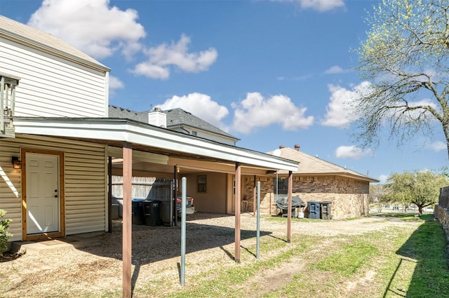back of property featuring a carport and brick siding