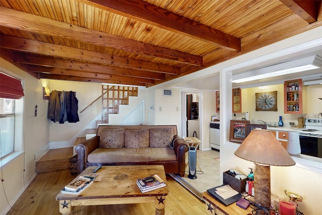 living area featuring stairway, visible vents, beam ceiling, and light wood finished floors