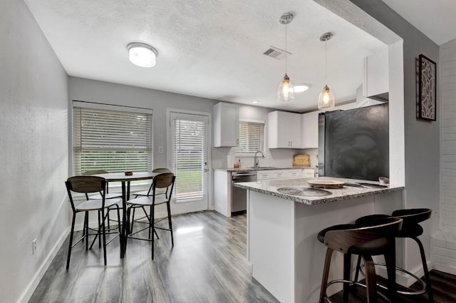 kitchen with stainless steel dishwasher, freestanding refrigerator, baseboards, light wood-style flooring, and a breakfast bar area