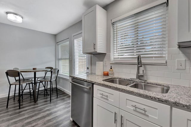 kitchen featuring dishwasher, backsplash, baseboards, and a sink
