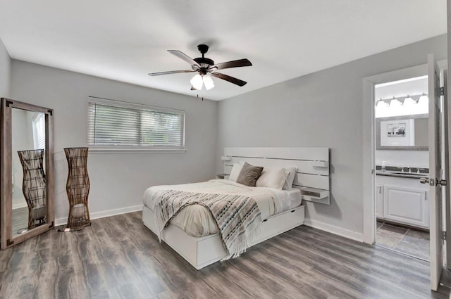 bedroom with wood finished floors, a sink, ensuite bath, baseboards, and ceiling fan