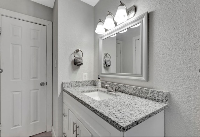 bathroom with a textured wall and vanity