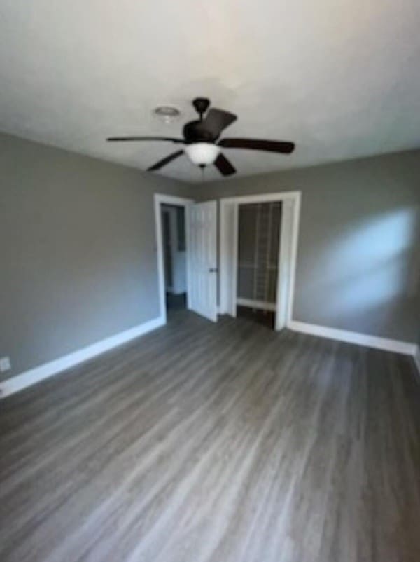 unfurnished bedroom with ceiling fan, baseboards, and wood finished floors